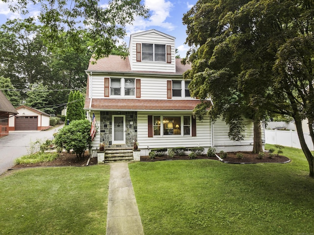 american foursquare style home featuring an outdoor structure, fence, a front lawn, and a detached garage