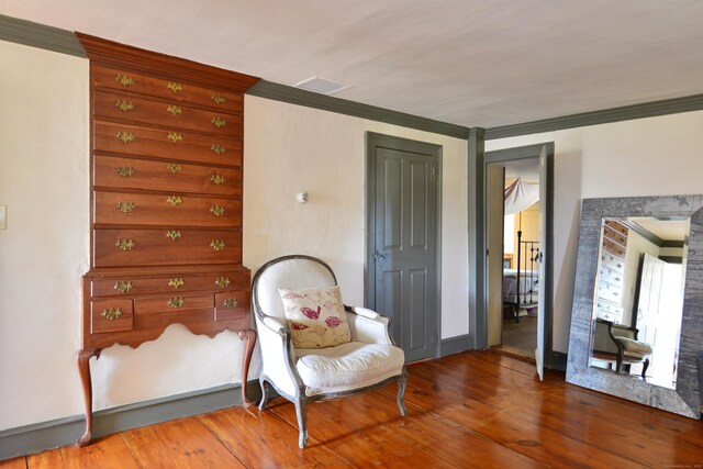 living area with crown molding, baseboards, and hardwood / wood-style flooring