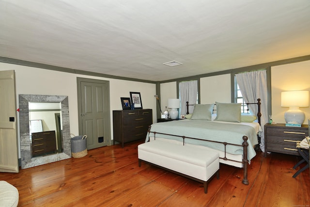 bedroom featuring a fireplace, wood finished floors, visible vents, and crown molding