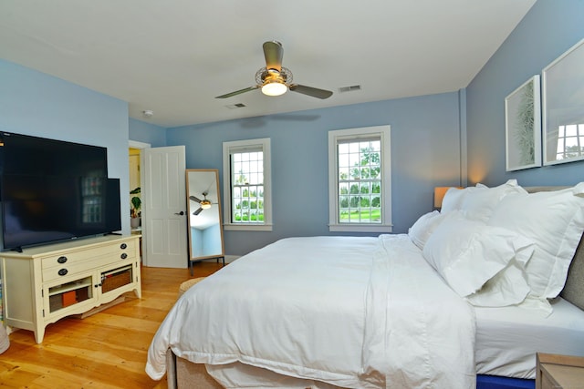 bedroom with light wood-style floors, visible vents, and a ceiling fan