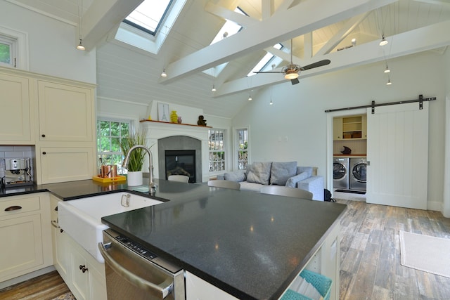 kitchen with a skylight, dark countertops, independent washer and dryer, open floor plan, and dishwasher