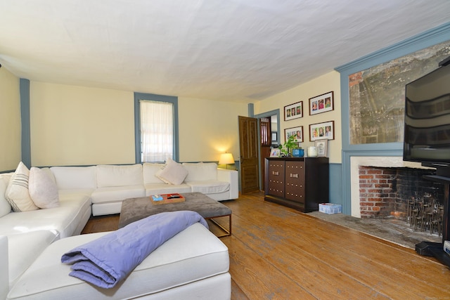 living area featuring a fireplace with flush hearth and wood finished floors