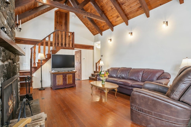 living room featuring wood ceiling, a stone fireplace, hardwood / wood-style floors, and beam ceiling