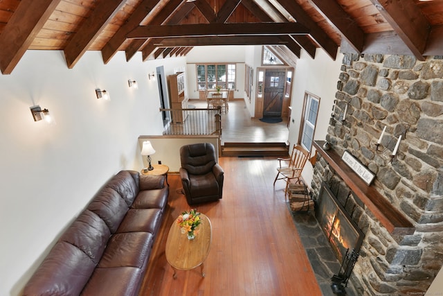 unfurnished living room with dark hardwood / wood-style flooring, a stone fireplace, vaulted ceiling with beams, and wood ceiling