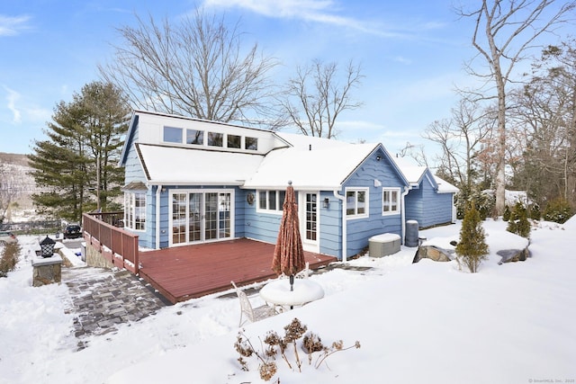 snow covered rear of property with a deck