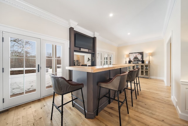 kitchen with ornamental molding, french doors, butcher block counters, and a kitchen bar