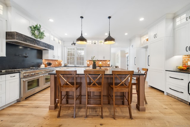 kitchen with range with two ovens, a kitchen island, white cabinetry, dark countertops, and glass insert cabinets