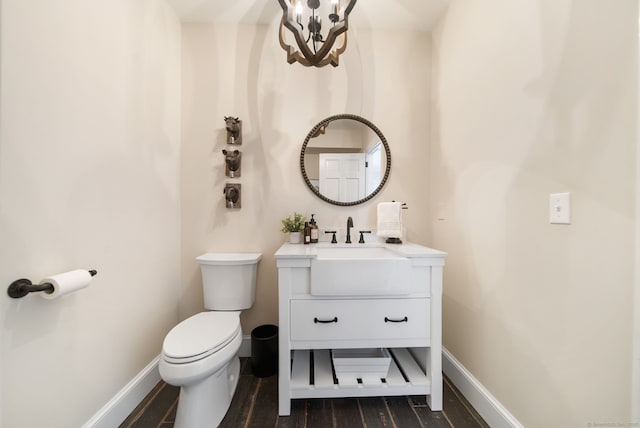 half bath featuring toilet, baseboards, wood finished floors, and vanity