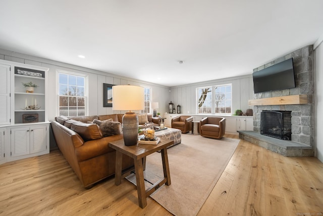 living area featuring a stone fireplace and light wood-style flooring