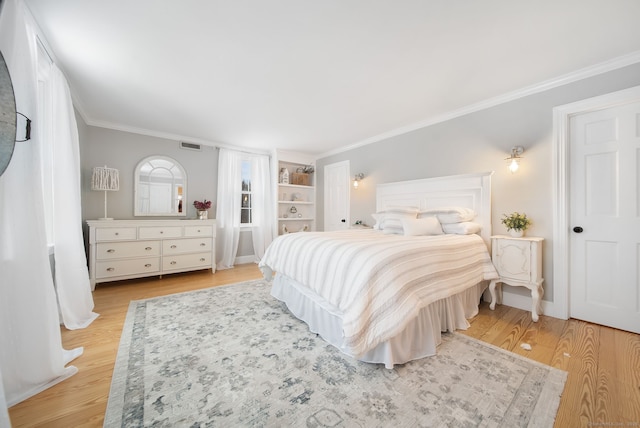 bedroom featuring light wood-type flooring, visible vents, crown molding, and baseboards