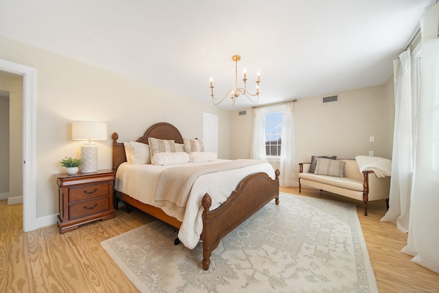 bedroom featuring baseboards, light wood-style floors, visible vents, and a notable chandelier