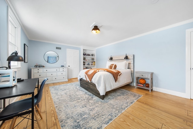 bedroom with light wood-style flooring, visible vents, baseboards, and crown molding