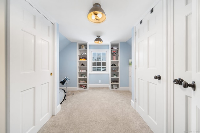 hallway featuring lofted ceiling, light colored carpet, and baseboards