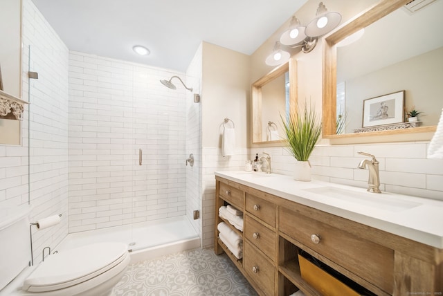 full bath with toilet, a shower stall, double vanity, and a sink