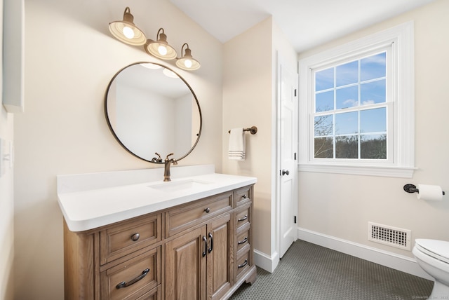 bathroom with toilet, vanity, visible vents, and baseboards