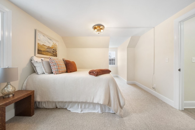 bedroom with light colored carpet, vaulted ceiling, and baseboards