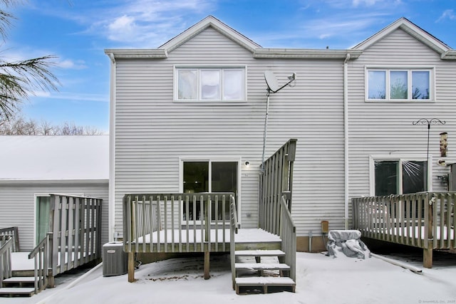 snow covered rear of property with a wooden deck and central air condition unit