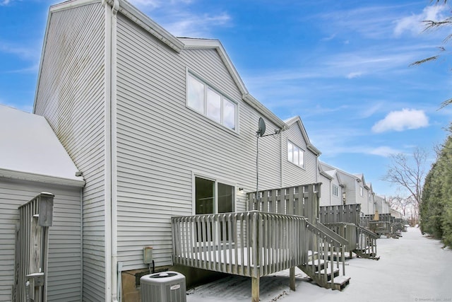 snow covered house featuring central AC unit and a deck