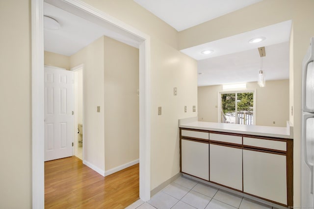 kitchen with hanging light fixtures, white cabinetry, and light tile patterned flooring