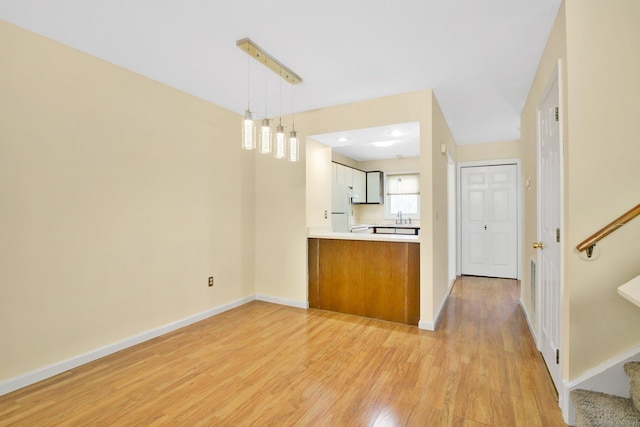 kitchen with pendant lighting, white cabinetry, sink, white refrigerator, and light wood-type flooring