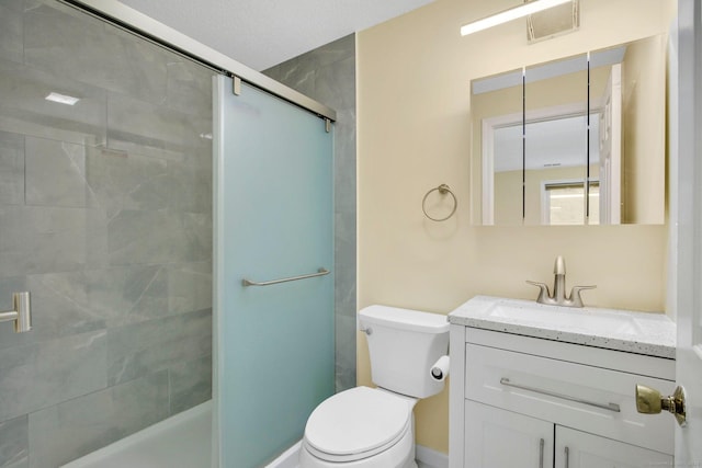 bathroom featuring vanity, toilet, and a shower with shower door