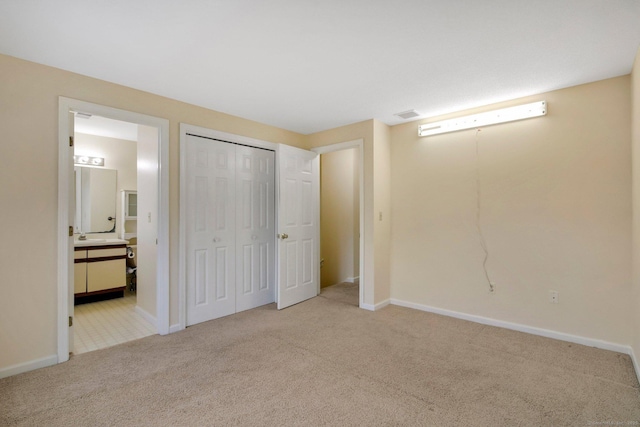 unfurnished bedroom featuring light colored carpet and connected bathroom