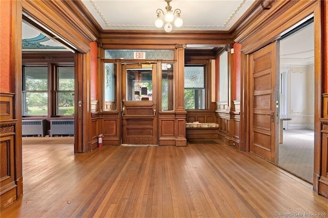 interior space featuring plenty of natural light, ornamental molding, radiator, and light wood-type flooring