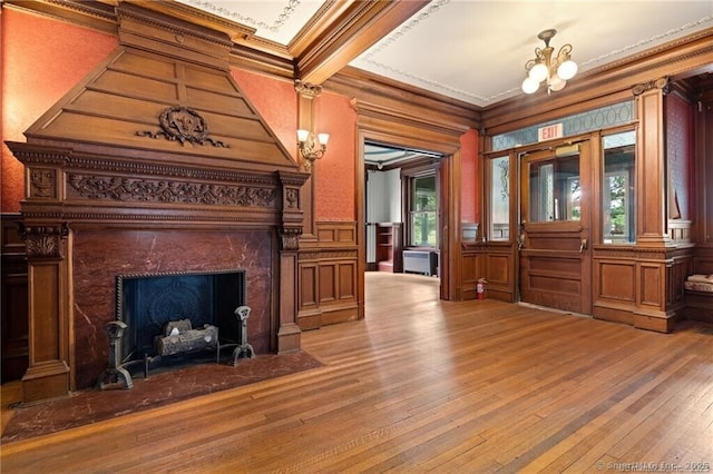 interior space with a notable chandelier, hardwood / wood-style flooring, ornamental molding, and a premium fireplace