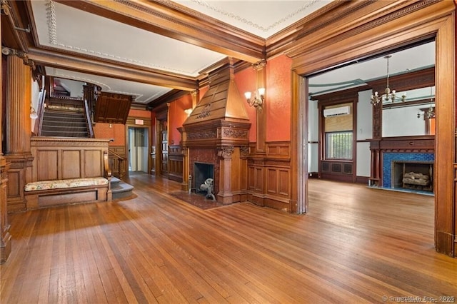 unfurnished living room with ornamental molding, hardwood / wood-style floors, and an inviting chandelier