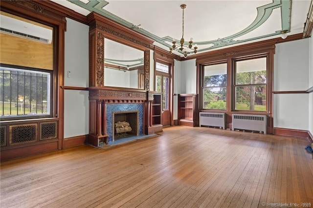 unfurnished living room featuring a tiled fireplace, radiator, a wall mounted air conditioner, and light hardwood / wood-style floors