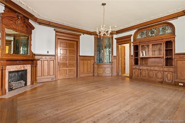 unfurnished living room with ornamental molding, hardwood / wood-style floors, a notable chandelier, and a fireplace