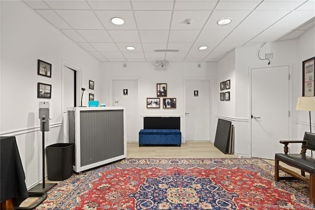 living room featuring wood-type flooring and a drop ceiling