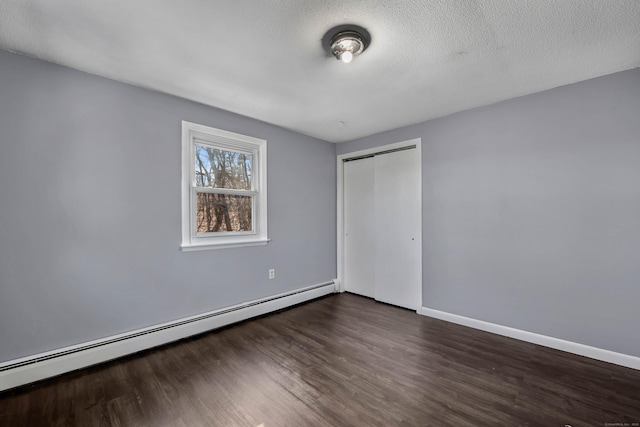 unfurnished bedroom with a baseboard radiator, dark wood-type flooring, a textured ceiling, and a closet