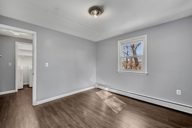 spare room with baseboard heating, washing machine and clothes dryer, dark hardwood / wood-style floors, and a textured ceiling