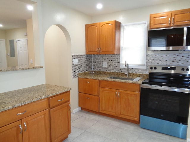 kitchen with stainless steel appliances, sink, backsplash, and light stone counters