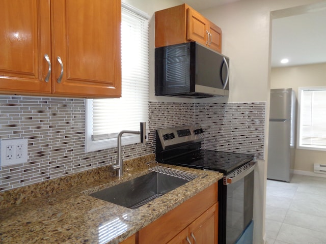 kitchen with sink, light tile patterned floors, backsplash, stainless steel appliances, and light stone countertops