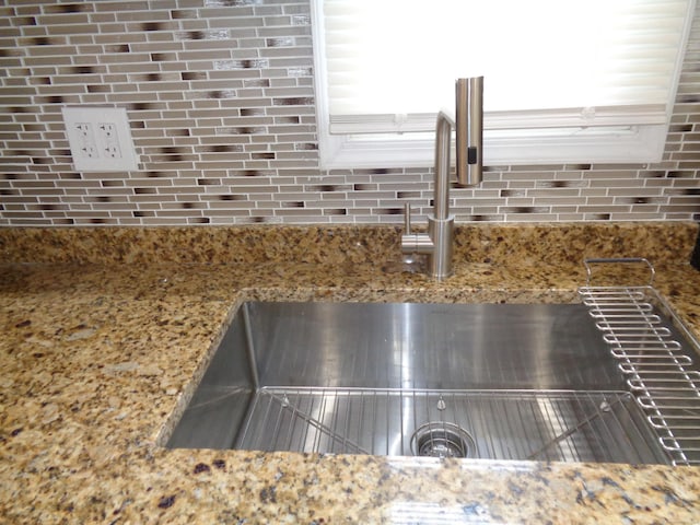 details with sink, decorative backsplash, and stone counters