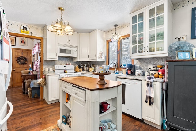 kitchen featuring white appliances, white cabinets, a kitchen island, decorative light fixtures, and a chandelier