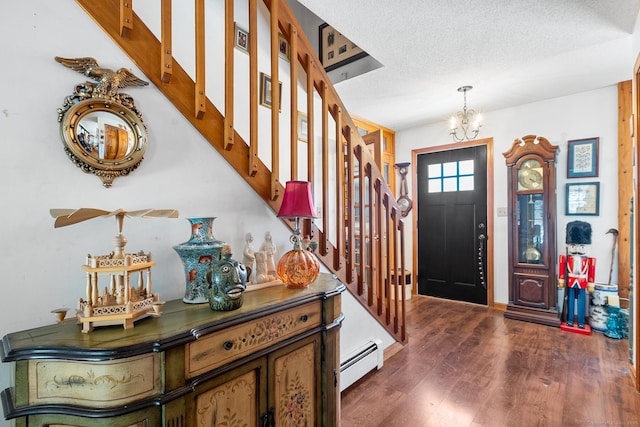 entryway featuring dark wood-type flooring, a chandelier, a textured ceiling, and a baseboard heating unit