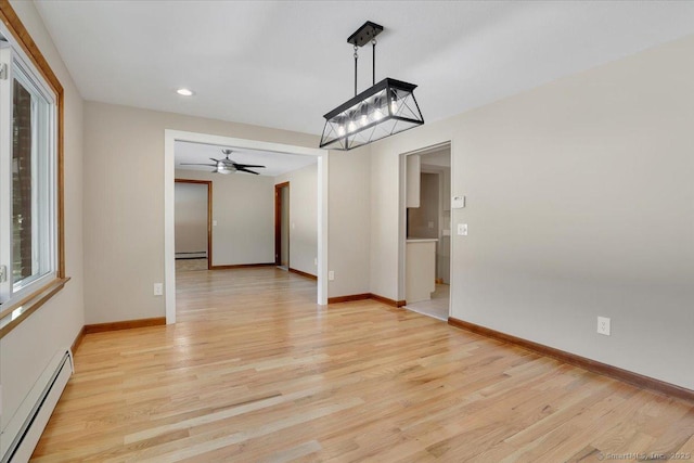 unfurnished dining area with ceiling fan, baseboard heating, and light hardwood / wood-style flooring