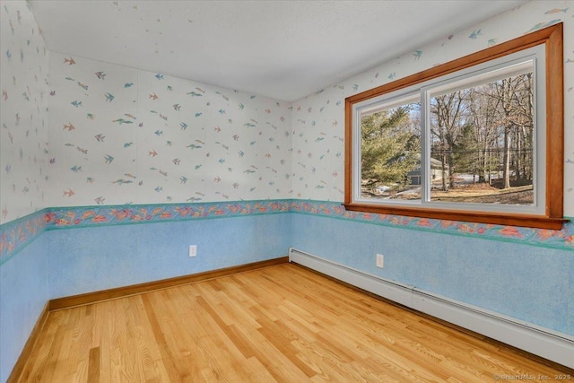 spare room with wood-type flooring and a baseboard heating unit