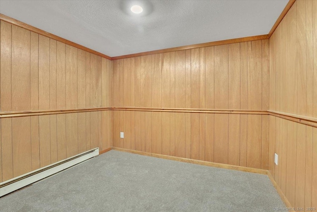 empty room featuring a baseboard radiator, wooden walls, light carpet, and a textured ceiling