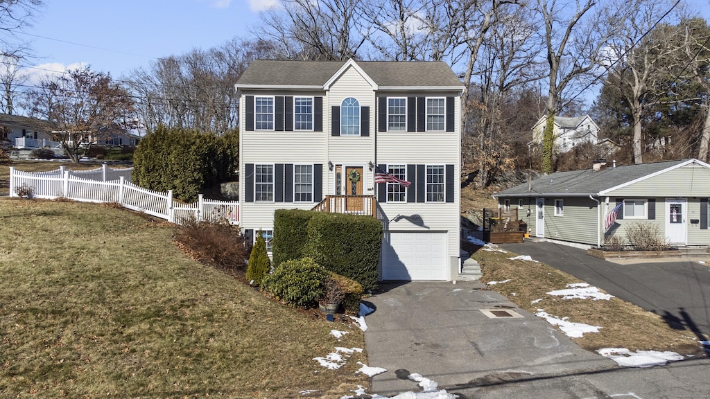 colonial home featuring a garage and a front lawn