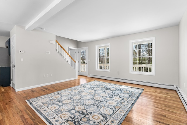 living area featuring a baseboard radiator, wood finished floors, baseboards, stairway, and beamed ceiling