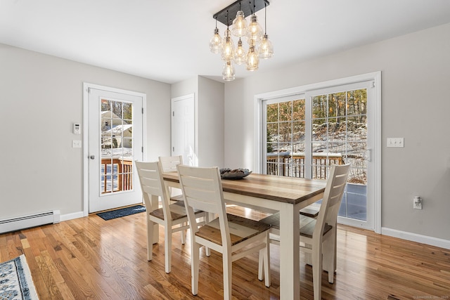 dining room featuring baseboard heating, an inviting chandelier, light wood-style flooring, and baseboards