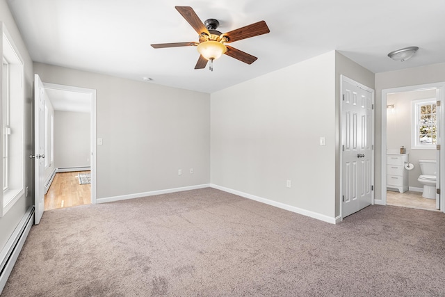 unfurnished bedroom featuring baseboards, a ceiling fan, light colored carpet, ensuite bathroom, and baseboard heating