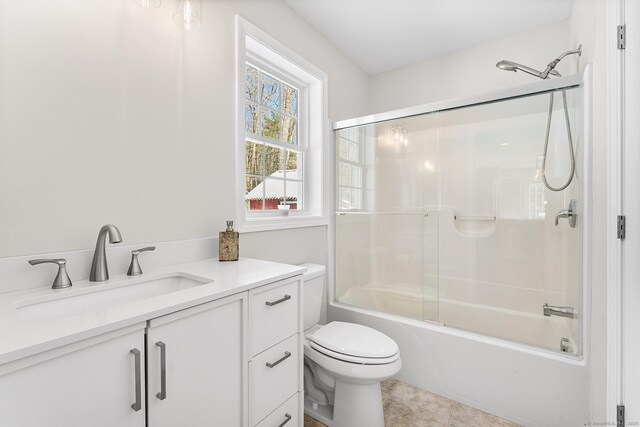 bathroom featuring toilet, bath / shower combo with glass door, and vanity