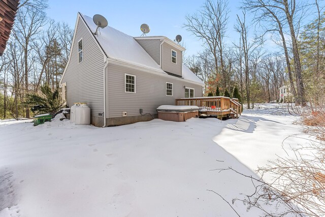 view of snowy exterior featuring a deck and a hot tub