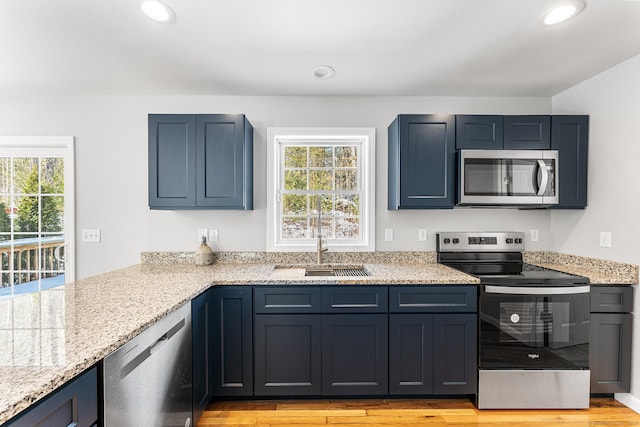 kitchen with stainless steel appliances, recessed lighting, light wood-type flooring, and a sink