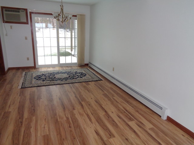 interior space with baseboard heating, wood-type flooring, a wall unit AC, and a notable chandelier